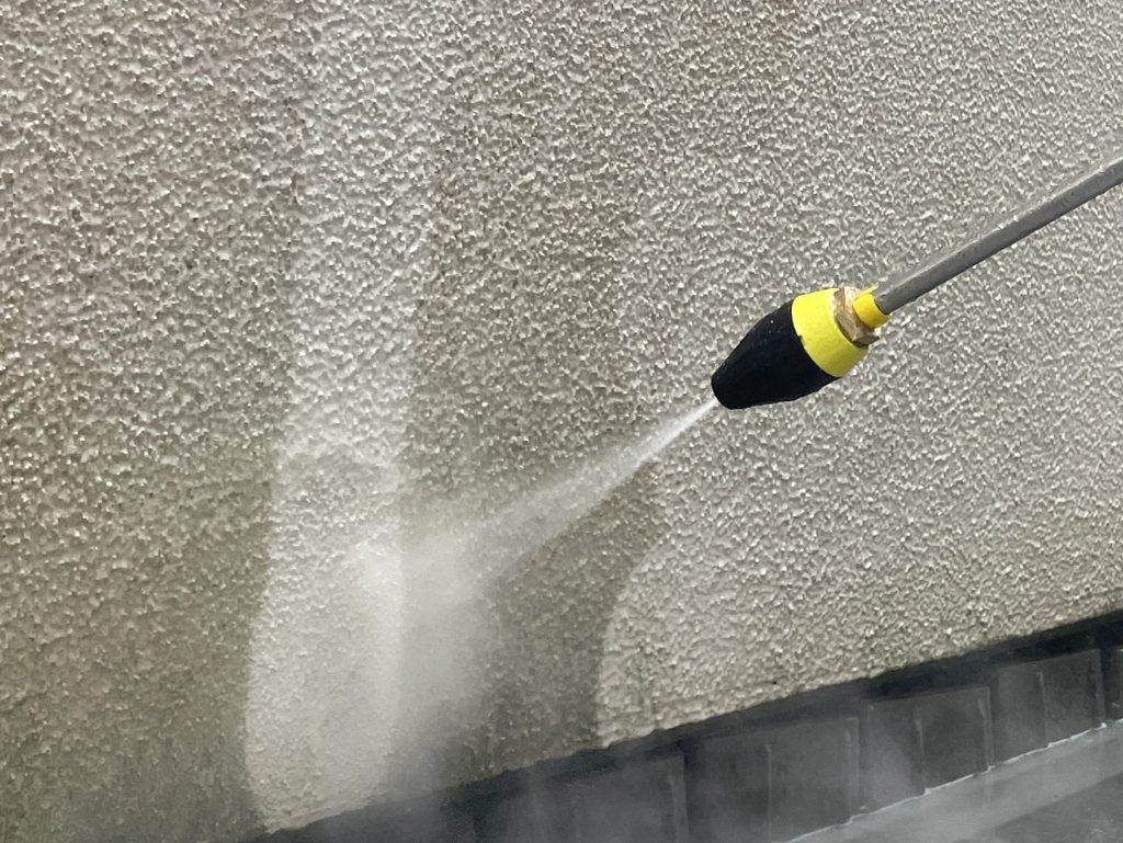 Die Fassadenreinigung einer dreckigen Fläche mit einem professionellen Reinigungsgerät