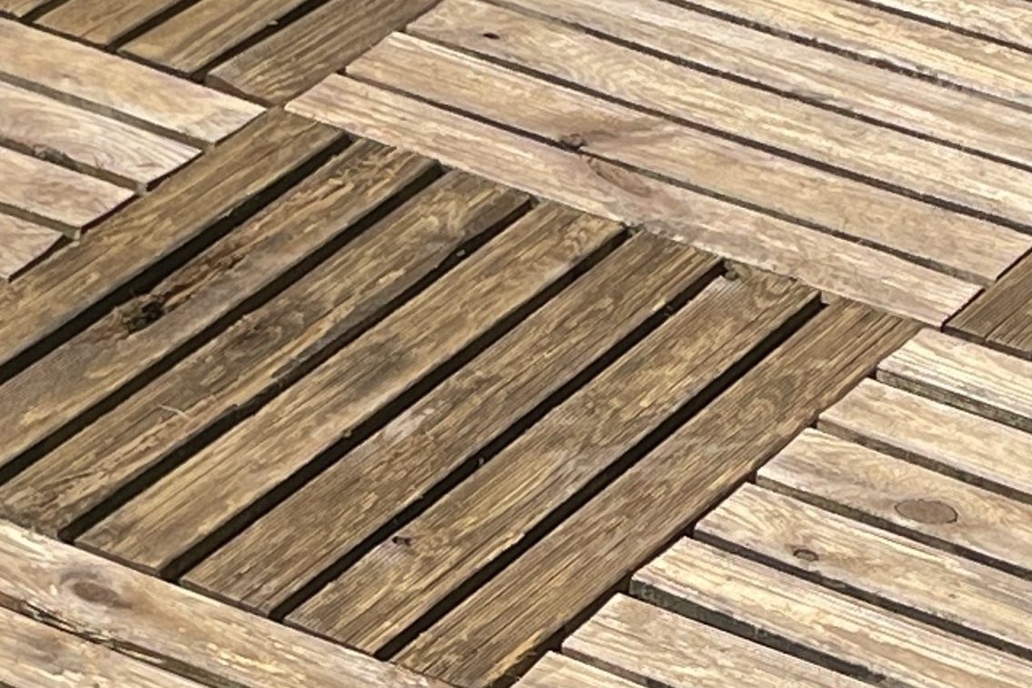 Ein frisch gereinigter, glänzender Holzboden in einer Terrasse. Ergebnis einer Terrassenreinigung.