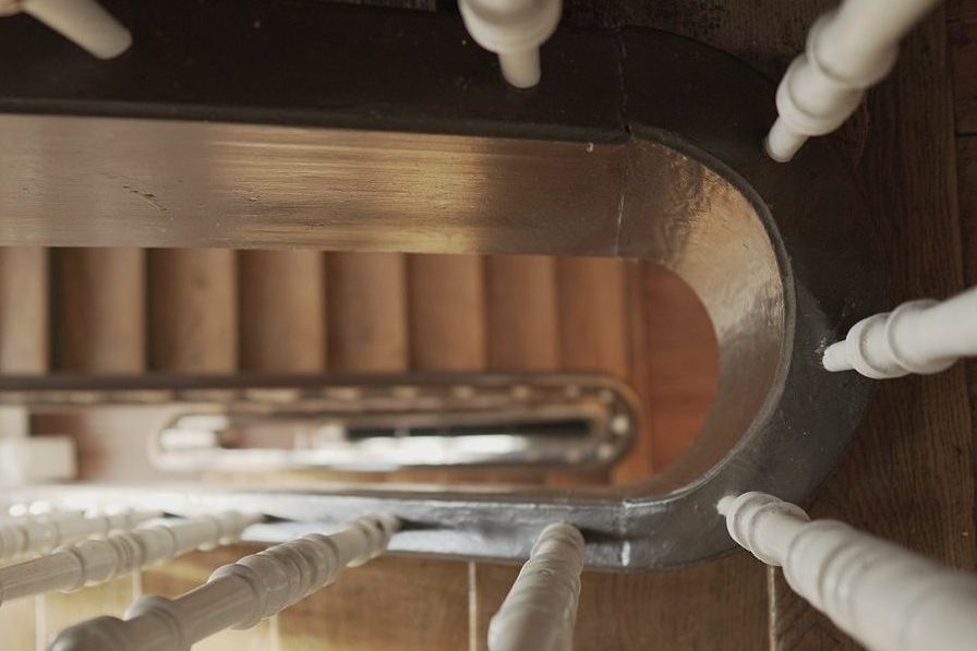 Eine saubere, weiße Treppe mit Holzstufen in einem Treppenhaus